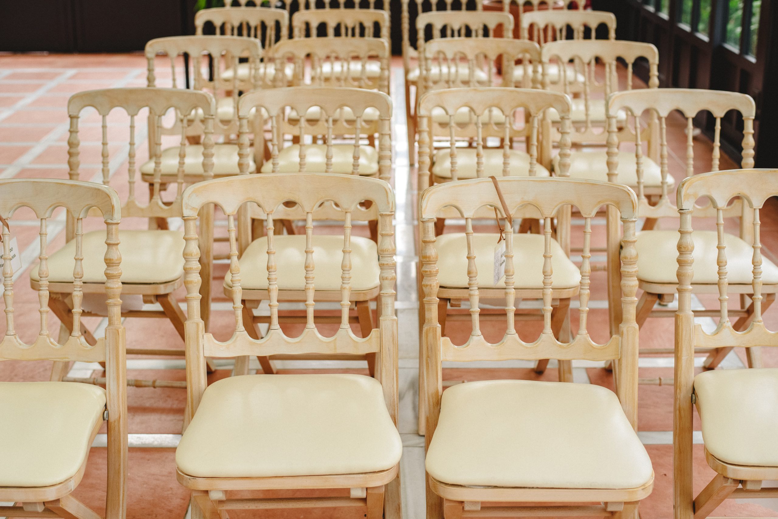 Many empty white wooden chairs lined up for a retro style event.